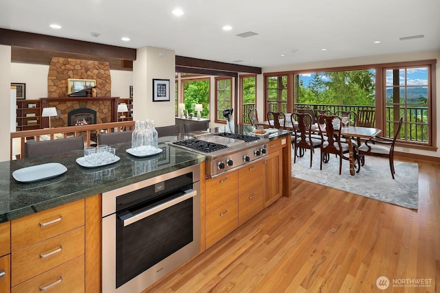 kitchen featuring a fireplace, stainless steel appliances, and light wood-type flooring