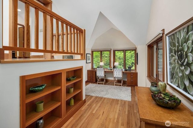 office area with high vaulted ceiling and light hardwood / wood-style floors