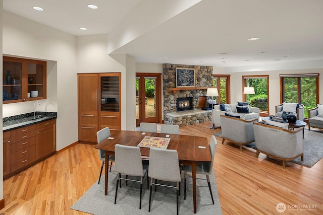 dining area featuring light wood-type flooring, indoor wet bar, and a fireplace