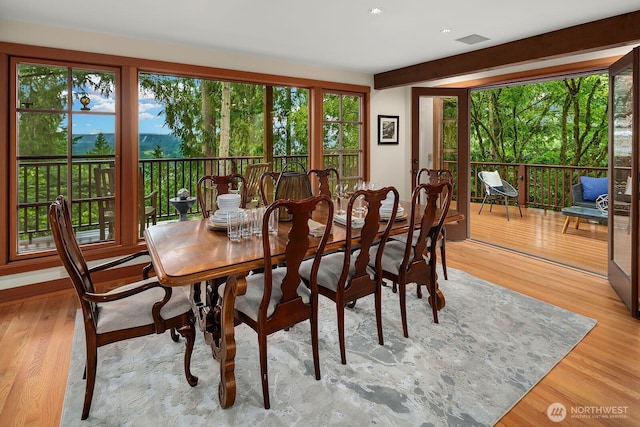 dining room featuring beamed ceiling and light hardwood / wood-style floors