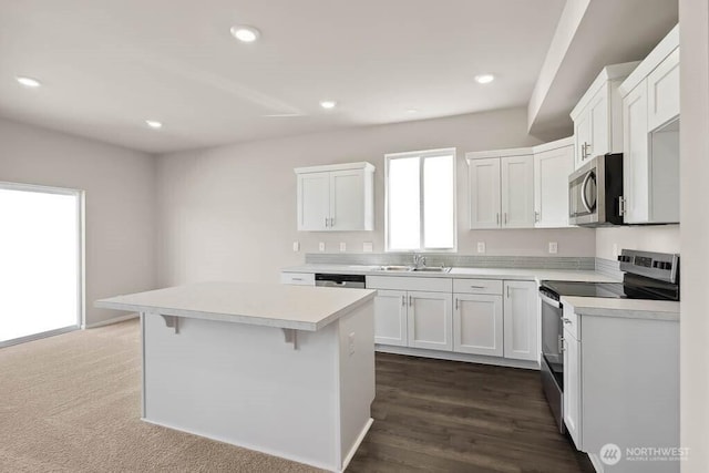 kitchen featuring recessed lighting, light countertops, white cabinets, appliances with stainless steel finishes, and a center island