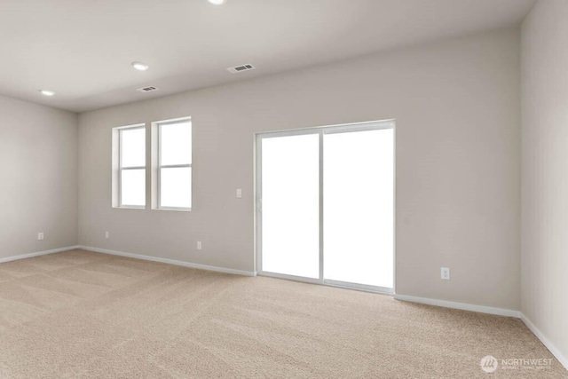 empty room featuring visible vents, light carpet, and baseboards