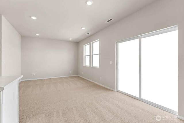 empty room featuring recessed lighting, light colored carpet, visible vents, and baseboards