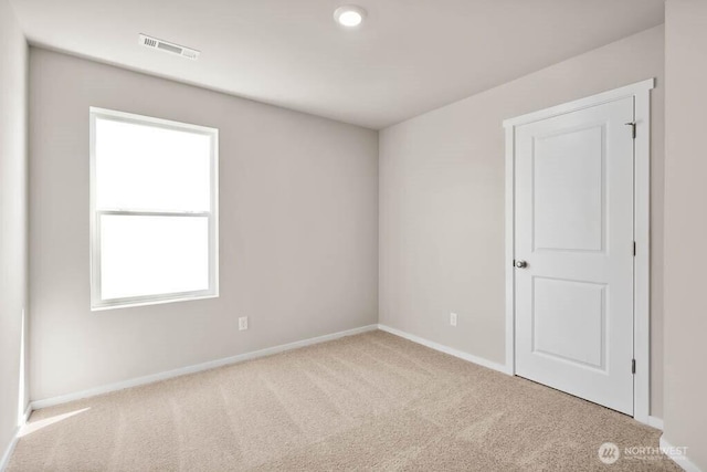 carpeted spare room featuring baseboards and visible vents