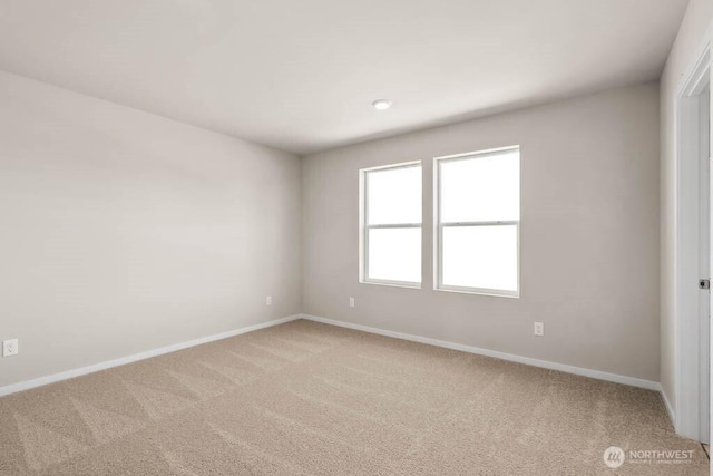 unfurnished room featuring light carpet and baseboards