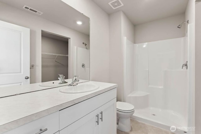 bathroom featuring visible vents, a stall shower, toilet, and vanity