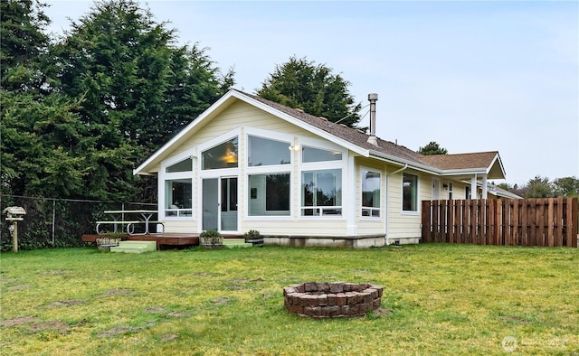 back of property featuring a fire pit, a lawn, and fence