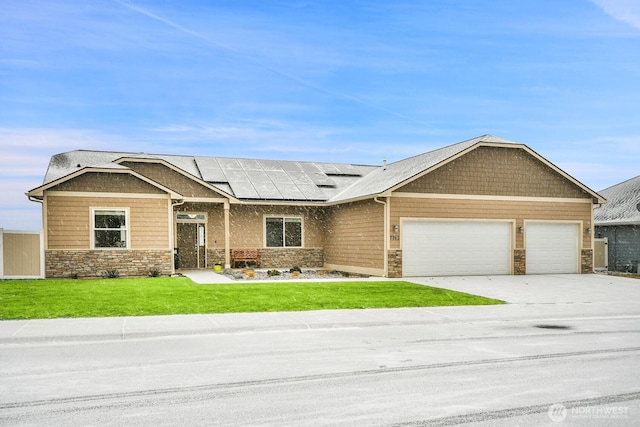 craftsman-style home with an attached garage, stone siding, driveway, roof mounted solar panels, and a front lawn