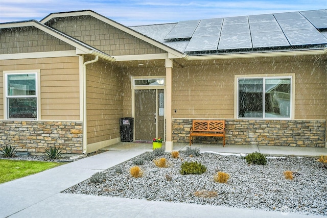 property entrance featuring stone siding and roof mounted solar panels