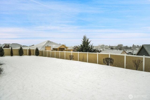 yard covered in snow featuring fence and a residential view