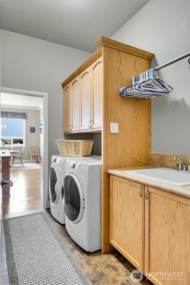 laundry room with wood finished floors, washer and clothes dryer, a sink, and cabinet space