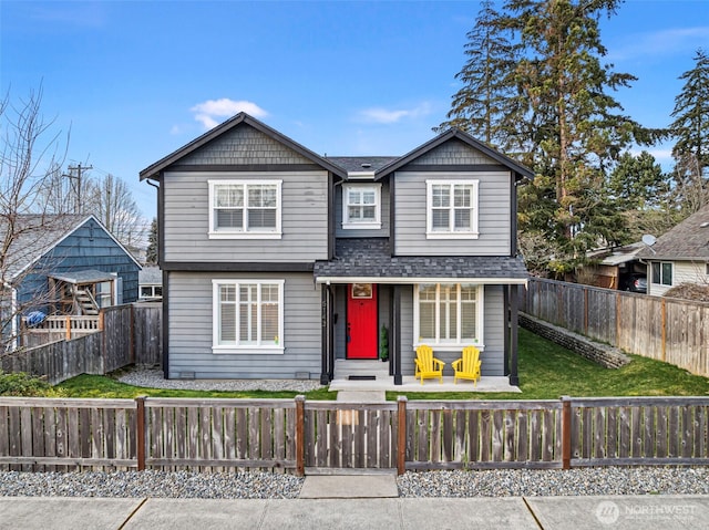 view of front of property featuring roof with shingles, a fenced front yard, and a front yard