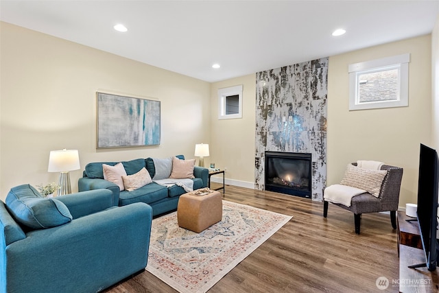 living area featuring a premium fireplace, wood finished floors, and recessed lighting