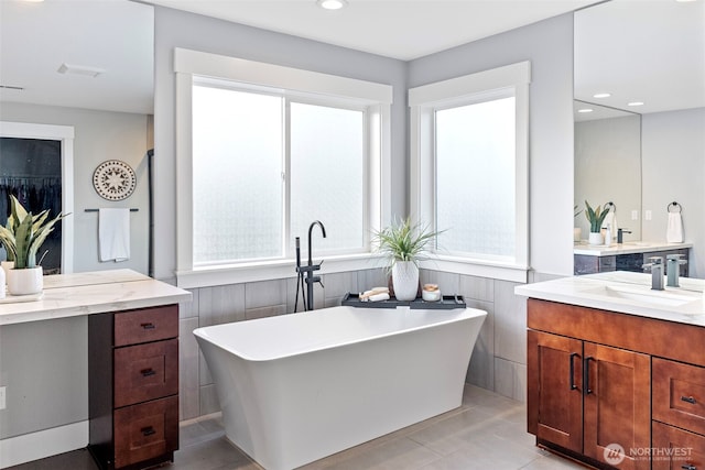 bathroom with recessed lighting, visible vents, vanity, a freestanding tub, and tile patterned floors