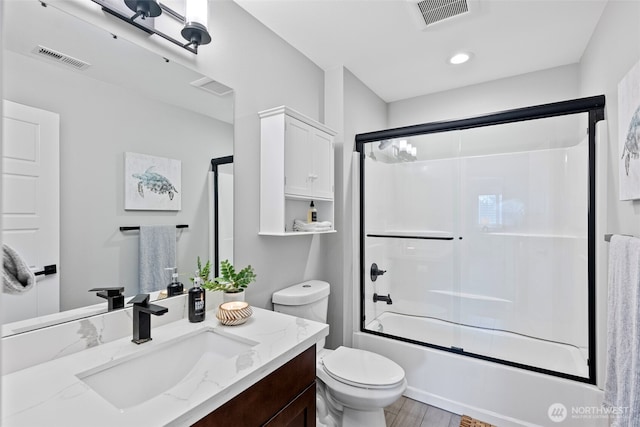 full bath featuring toilet, enclosed tub / shower combo, visible vents, and vanity