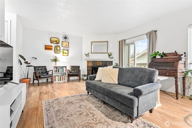 living area featuring light wood-type flooring and a tile fireplace