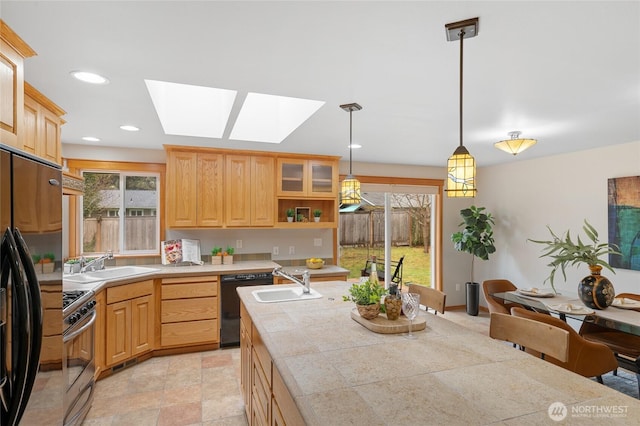 kitchen featuring glass insert cabinets, decorative light fixtures, light brown cabinetry, black appliances, and a sink