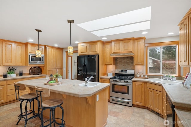 kitchen with a kitchen island with sink, under cabinet range hood, light countertops, black appliances, and a sink