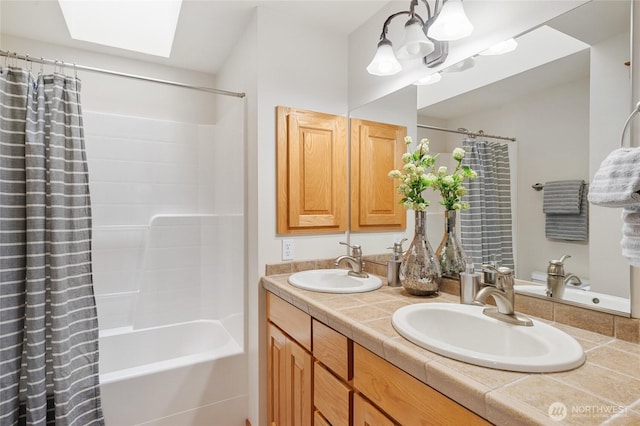 bathroom with double vanity, shower / tub combo, a skylight, and a sink