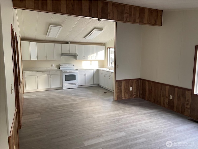 kitchen with wooden walls, sink, white cabinets, electric range, and light wood-type flooring