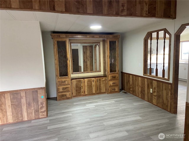 unfurnished room featuring light hardwood / wood-style flooring and wood walls