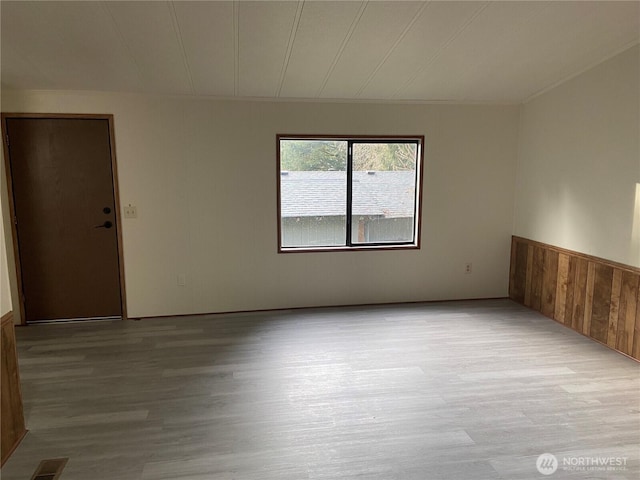 spare room with wooden walls and light wood-type flooring