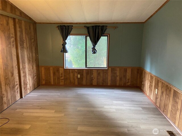 spare room with light hardwood / wood-style floors and wood walls