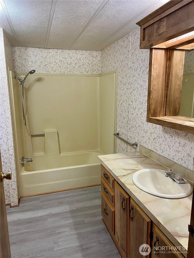 bathroom with vanity, hardwood / wood-style floors, a textured ceiling, and washtub / shower combination