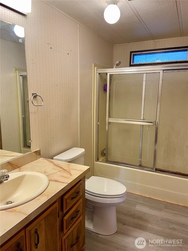 full bathroom with toilet, vanity, bath / shower combo with glass door, and hardwood / wood-style floors