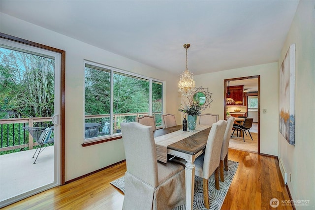 dining space featuring a notable chandelier, baseboards, and light wood-style floors