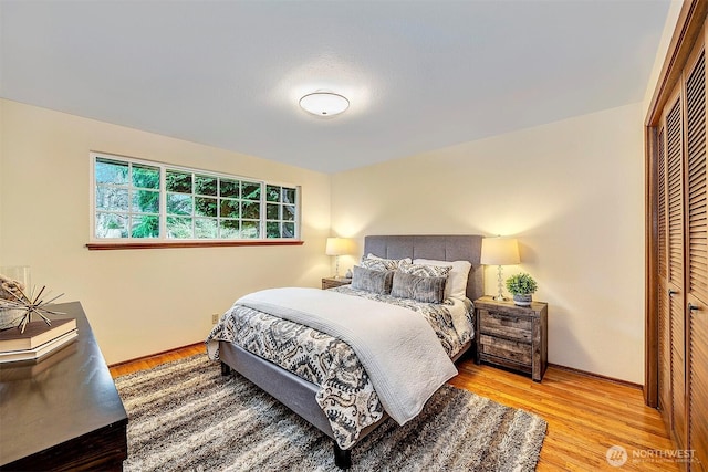 bedroom with a closet, baseboards, and light wood finished floors