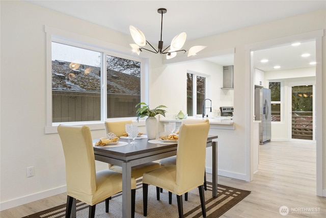 dining area featuring light wood-type flooring, baseboards, a chandelier, and recessed lighting