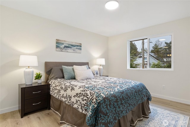 bedroom featuring light wood finished floors and baseboards