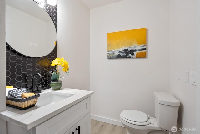 bathroom featuring baseboards, vanity, toilet, and wood finished floors