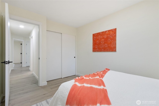 bedroom featuring light wood finished floors, a closet, and baseboards