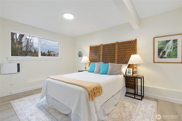 bedroom featuring baseboards, beam ceiling, and wood finished floors