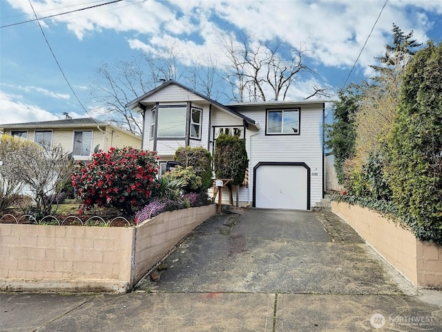 view of front of property featuring driveway, a garage, and fence