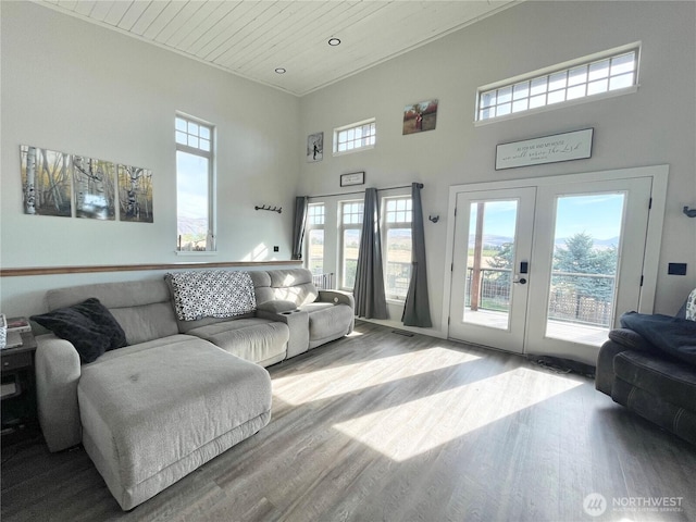 living area with wooden ceiling, recessed lighting, a high ceiling, wood finished floors, and french doors