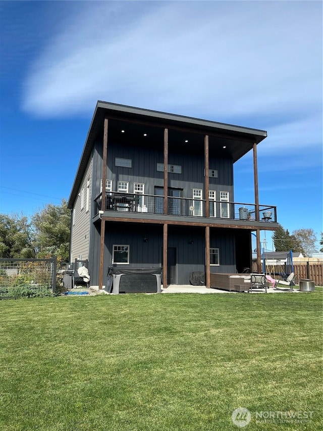 rear view of property featuring fence, a lawn, and board and batten siding