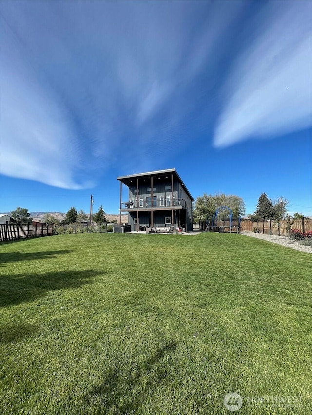 back of property featuring fence, a playground, and a yard