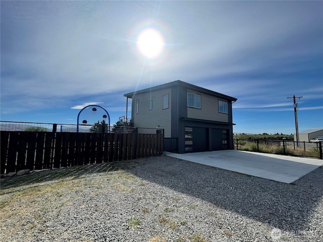 view of property exterior featuring a garage, concrete driveway, and fence