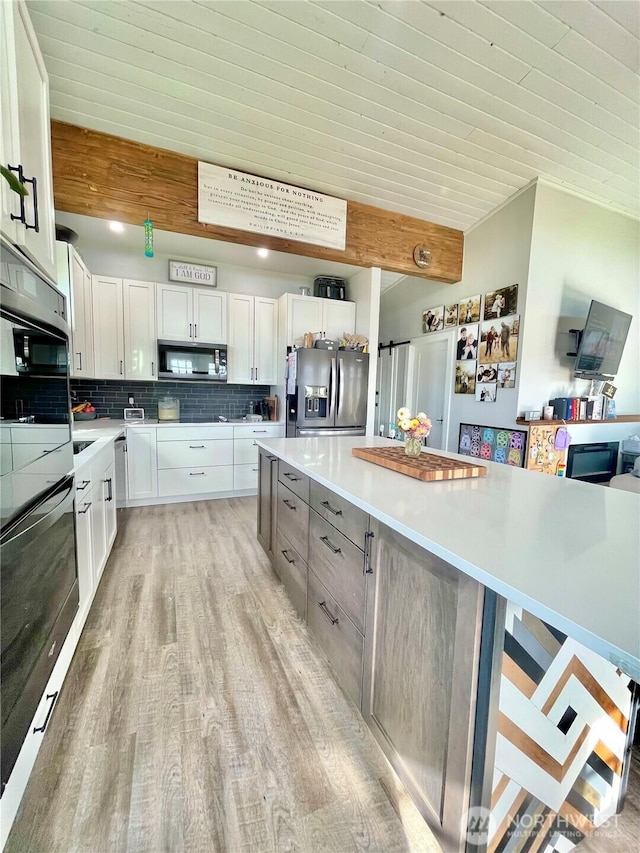 kitchen featuring light countertops, appliances with stainless steel finishes, light wood-style flooring, and tasteful backsplash