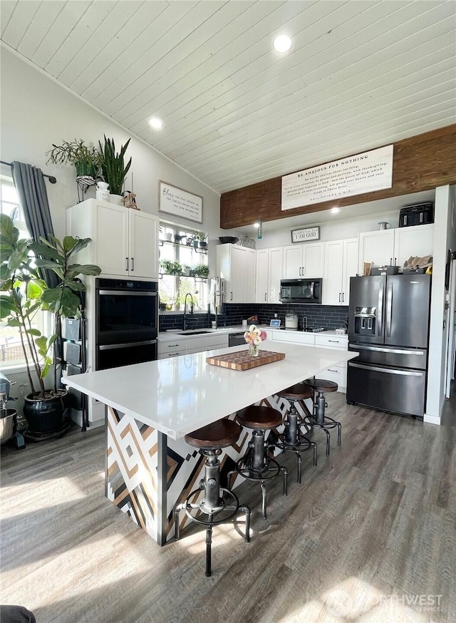 kitchen with black appliances, dark wood-style flooring, a sink, and white cabinetry