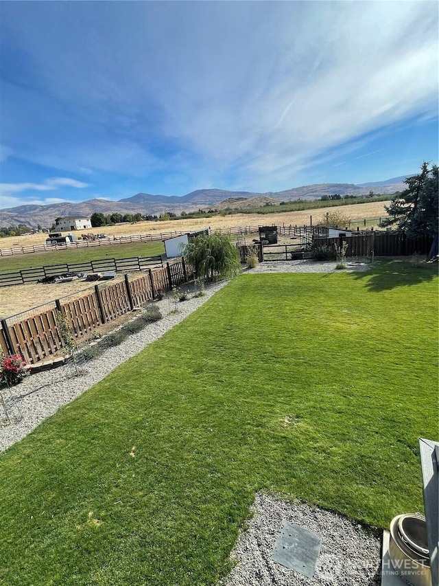 view of yard with a rural view, fence, and a mountain view