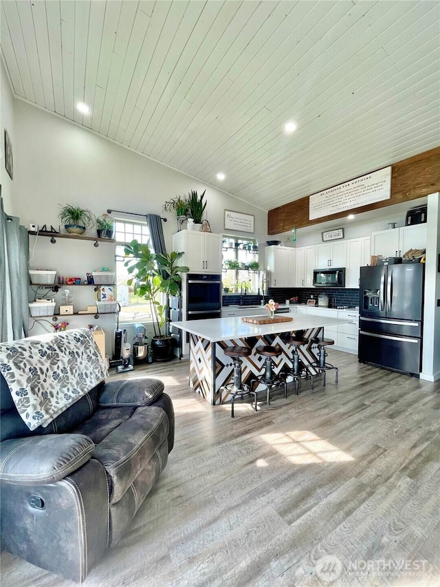 living room with high vaulted ceiling, recessed lighting, wood ceiling, and light wood-style flooring