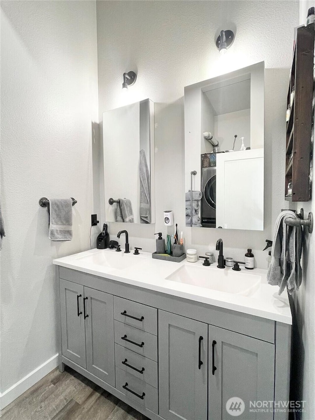 bathroom with double vanity, wood finished floors, a sink, and baseboards