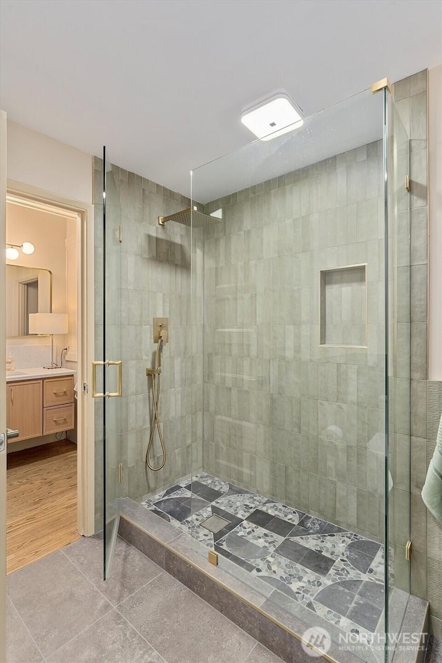 bathroom featuring tile patterned flooring, a shower stall, and vanity