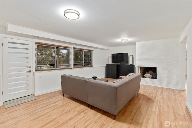 living room featuring light wood finished floors, a fireplace, and baseboards