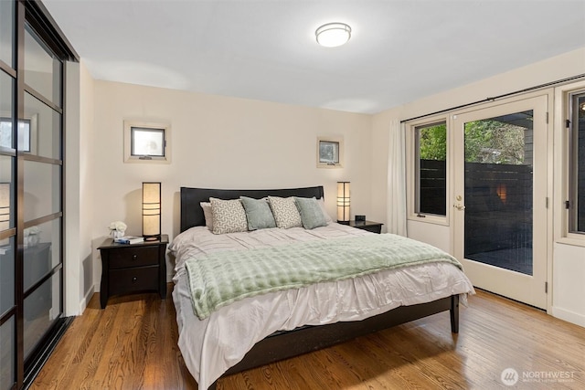 bedroom with access to outside, wood finished floors, and baseboards