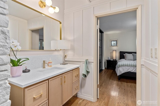 bathroom with wood finished floors, ensuite bath, vanity, and a decorative wall